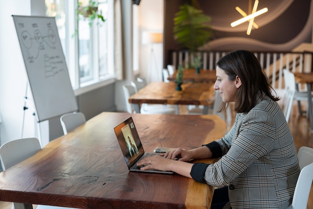 Choosing A Virtual Assistant Vendor A woman wearing a corporate attire, using a laptop on top of a wooden table.